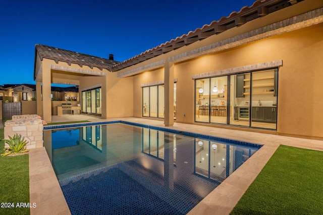 pool at night featuring a patio and area for grilling