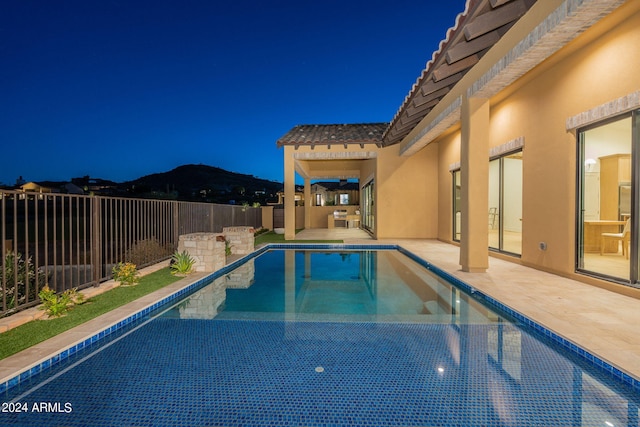 pool at night with a mountain view and a patio area