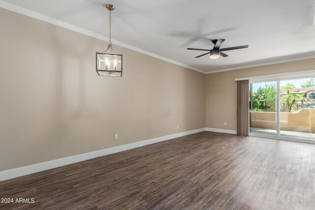 empty room featuring ornamental molding, dark hardwood / wood-style floors, and ceiling fan with notable chandelier