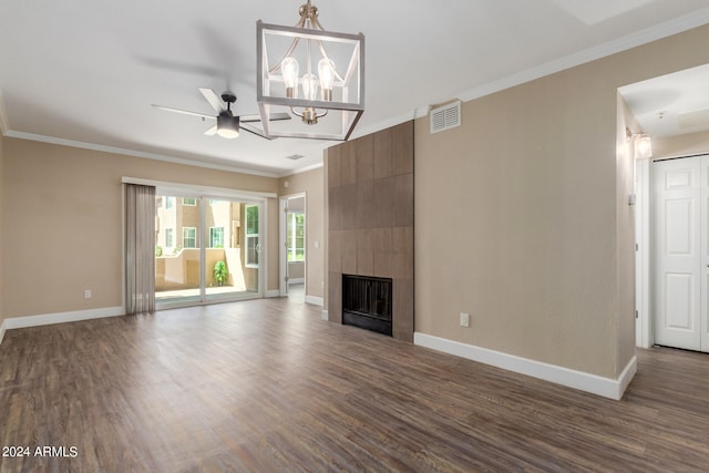 unfurnished living room featuring ceiling fan with notable chandelier, a tile fireplace, dark hardwood / wood-style flooring, and crown molding