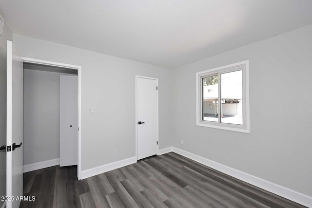 unfurnished bedroom with dark wood-style flooring and baseboards