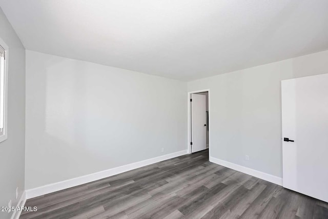 spare room featuring baseboards and wood finished floors