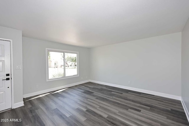 empty room featuring baseboards and dark wood-style flooring