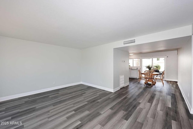 empty room with baseboards, visible vents, and dark wood finished floors