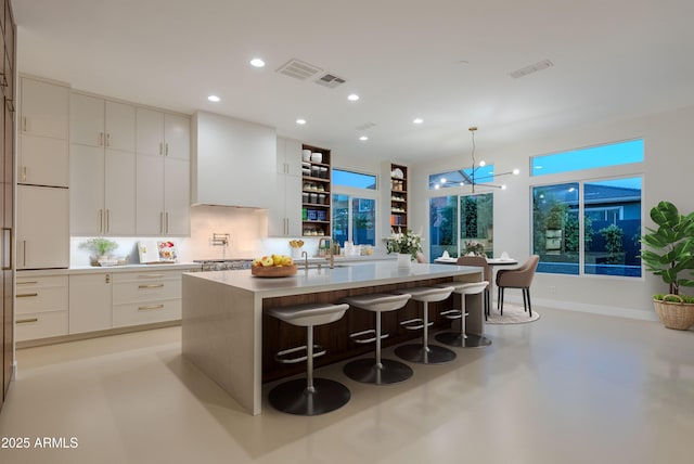 kitchen featuring a breakfast bar area, modern cabinets, recessed lighting, white cabinetry, and an island with sink