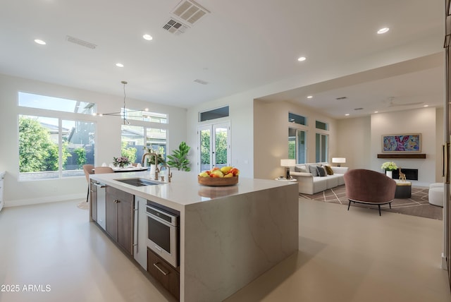 kitchen featuring visible vents, a fireplace, a sink, open floor plan, and recessed lighting