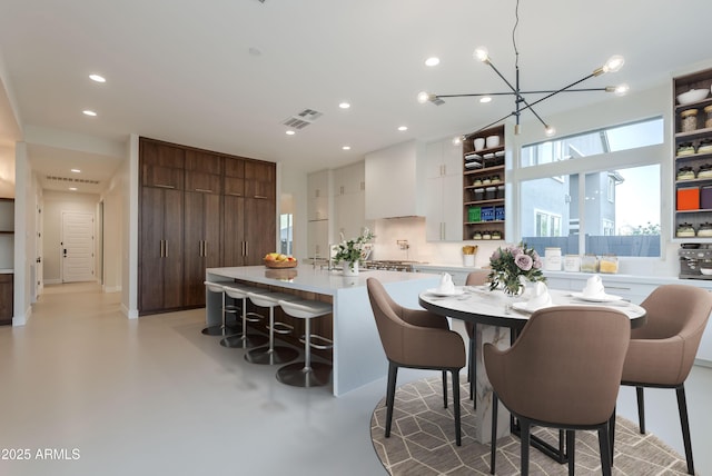 dining space with recessed lighting, concrete flooring, a chandelier, and visible vents