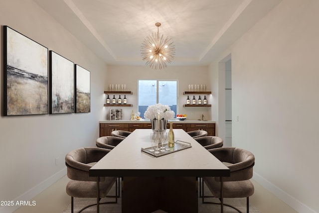 dining space with an inviting chandelier, baseboards, and a tray ceiling