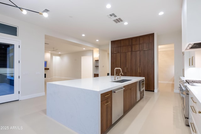 kitchen featuring a sink, modern cabinets, a center island with sink, and stainless steel appliances