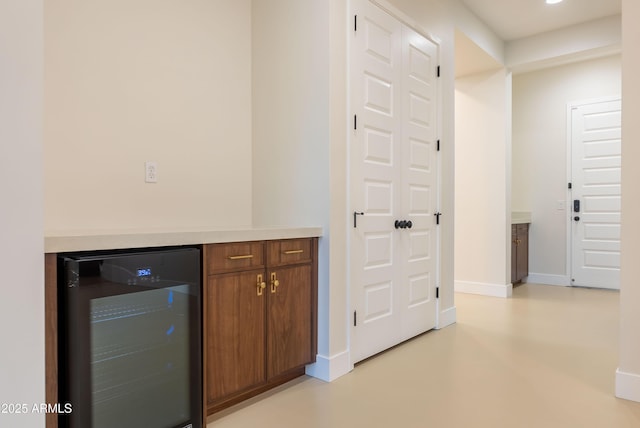 interior space featuring finished concrete flooring, baseboards, and beverage cooler