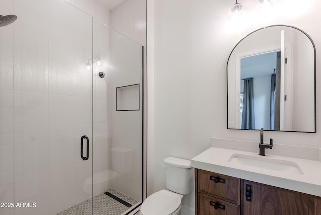 bathroom with toilet, a shower stall, and vanity