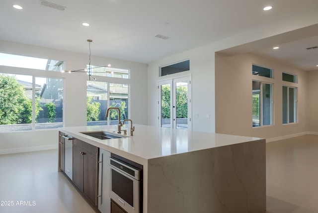 kitchen featuring visible vents, a sink, baseboards, and a healthy amount of sunlight
