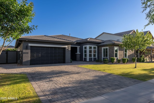 view of front of house featuring a tile roof, a garage, stucco siding, a front yard, and decorative driveway