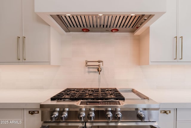 interior space featuring backsplash, white cabinetry, ventilation hood, and cooktop