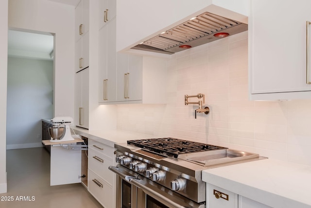 kitchen with backsplash, white cabinets, high end stainless steel range oven, and light countertops