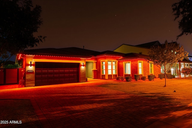 prairie-style home featuring an attached garage, driveway, a tile roof, and stucco siding