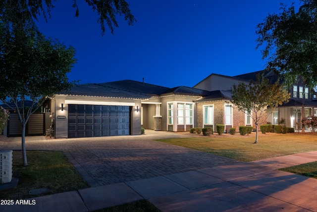 view of front of property featuring a lawn, decorative driveway, an attached garage, and stucco siding