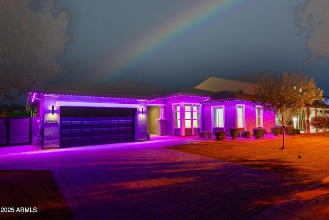 view of front of house with a garage, a tiled roof, stucco siding, and decorative driveway