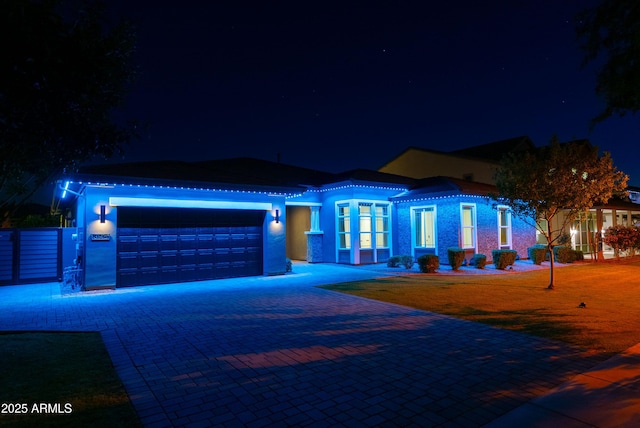 view of front of home featuring an attached garage, stucco siding, and decorative driveway