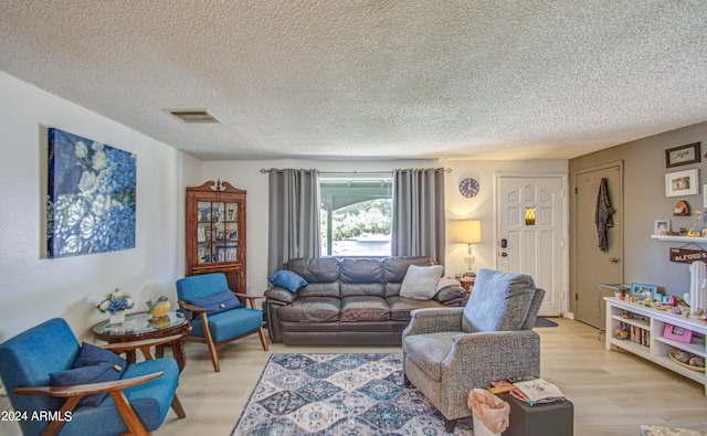 living room with a textured ceiling and light wood-type flooring