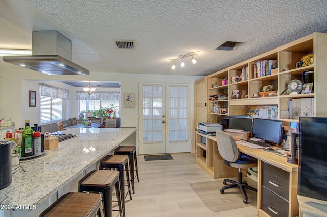 office space with light hardwood / wood-style floors, french doors, a textured ceiling, and an inviting chandelier