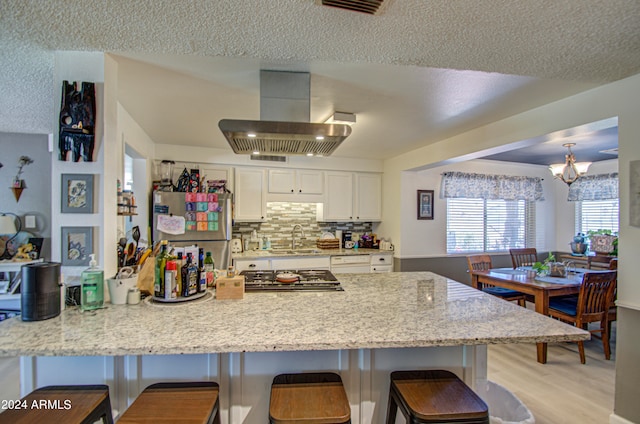 kitchen featuring island exhaust hood, stainless steel appliances, sink, white cabinets, and light hardwood / wood-style floors