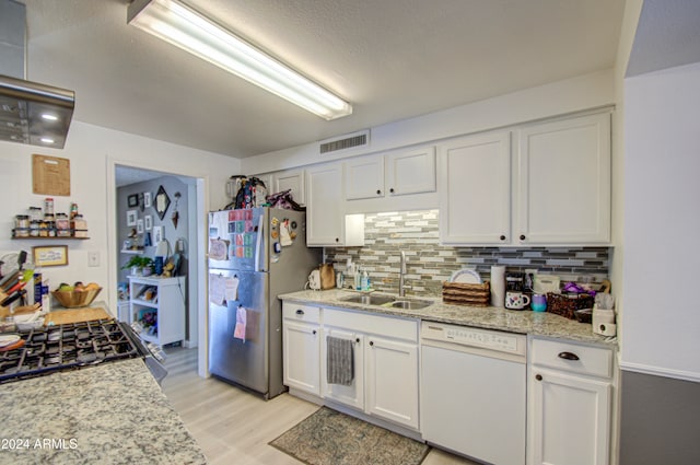 kitchen with appliances with stainless steel finishes, sink, light wood-type flooring, white cabinets, and decorative backsplash