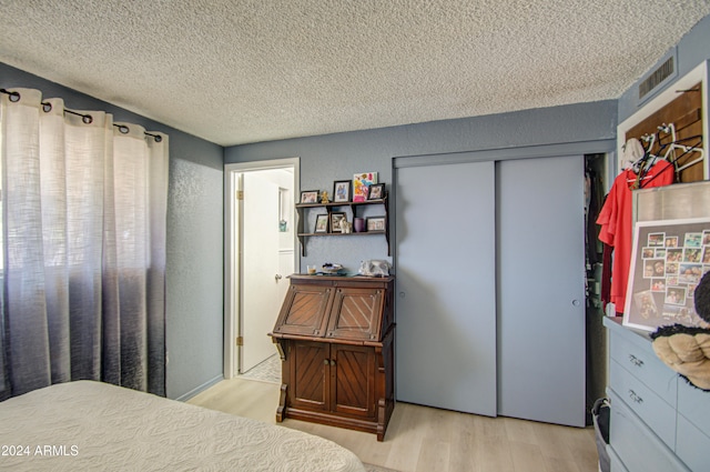 bedroom featuring a closet, a textured ceiling, and light wood-type flooring