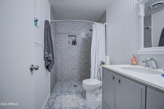 bathroom with vanity, a textured ceiling, walk in shower, and toilet