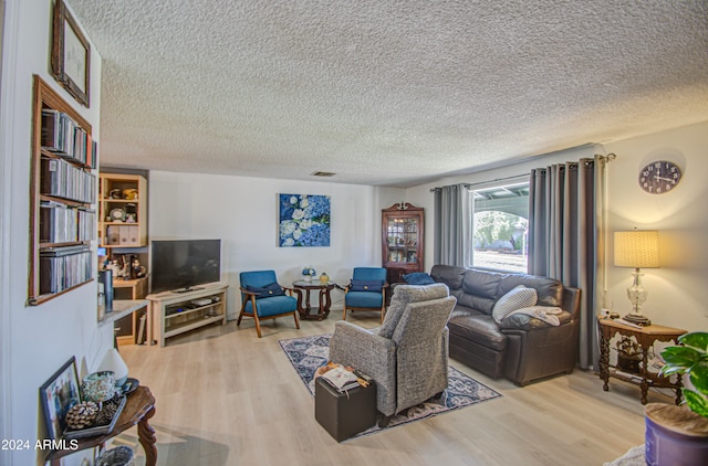 living room with a textured ceiling and light wood-type flooring