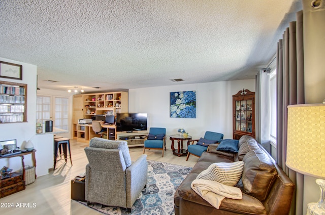 living room with a textured ceiling and light wood-type flooring