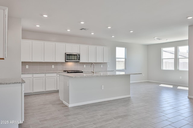 kitchen featuring visible vents, decorative backsplash, recessed lighting, stainless steel microwave, and white cabinets