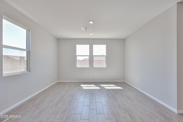 spare room featuring baseboards, light wood-style flooring, and visible vents