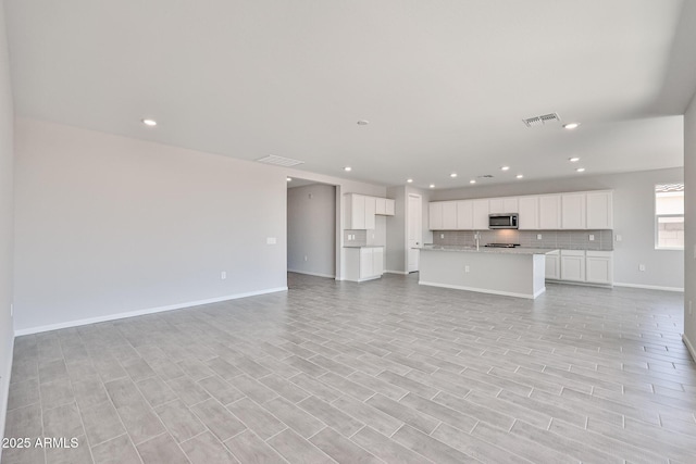 unfurnished living room with visible vents, recessed lighting, baseboards, and light wood-type flooring
