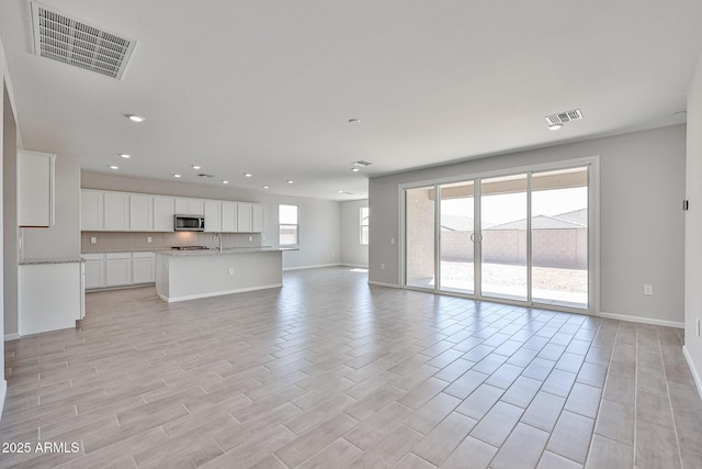 unfurnished living room featuring baseboards, light wood-type flooring, recessed lighting, and visible vents