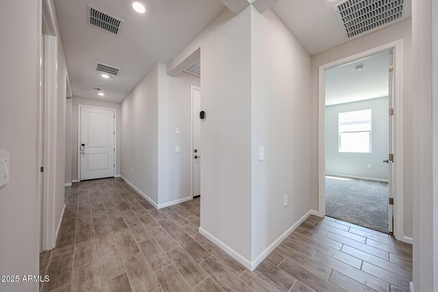 hallway featuring wood finish floors, visible vents, and baseboards