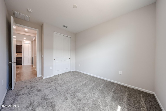 unfurnished bedroom with carpet floors, baseboards, visible vents, and a closet
