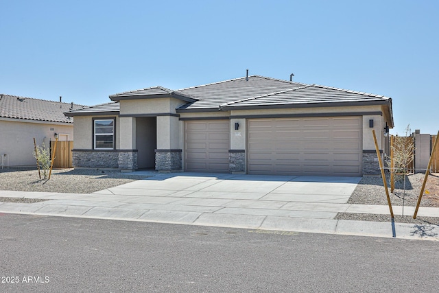 view of front of property featuring a garage, fence, concrete driveway, stone siding, and stucco siding