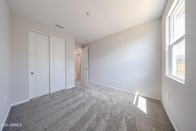 unfurnished bedroom with carpet floors, baseboards, visible vents, and a closet