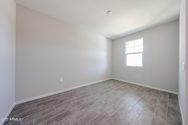 spare room with baseboards and wood finished floors