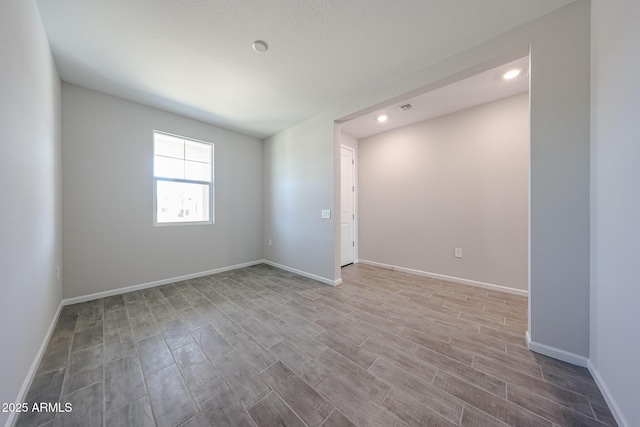 empty room featuring baseboards, recessed lighting, and wood finished floors