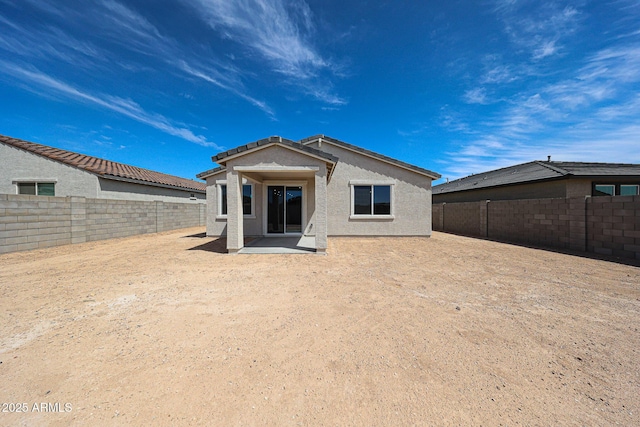 rear view of property with a fenced backyard, a patio area, and stucco siding
