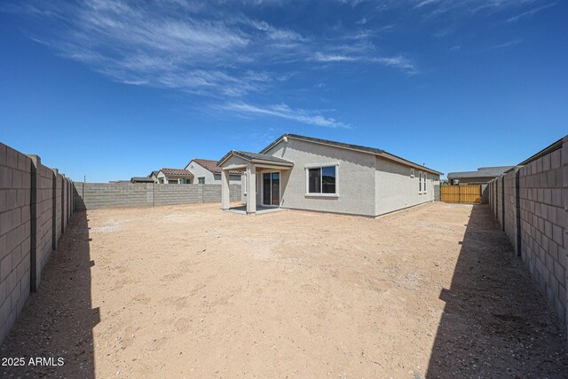 rear view of property featuring a fenced backyard and stucco siding