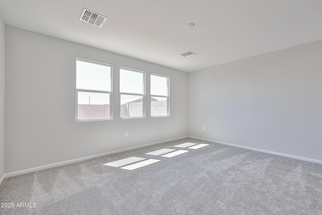 carpeted spare room featuring visible vents and baseboards
