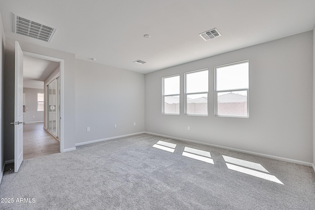 carpeted spare room with baseboards and visible vents