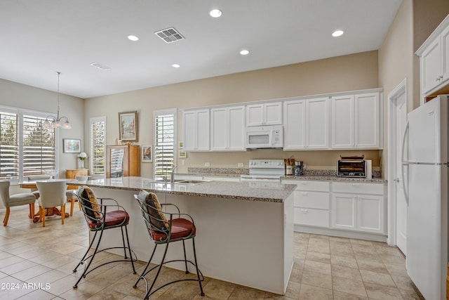 kitchen featuring white appliances, a center island with sink, white cabinetry, and decorative light fixtures