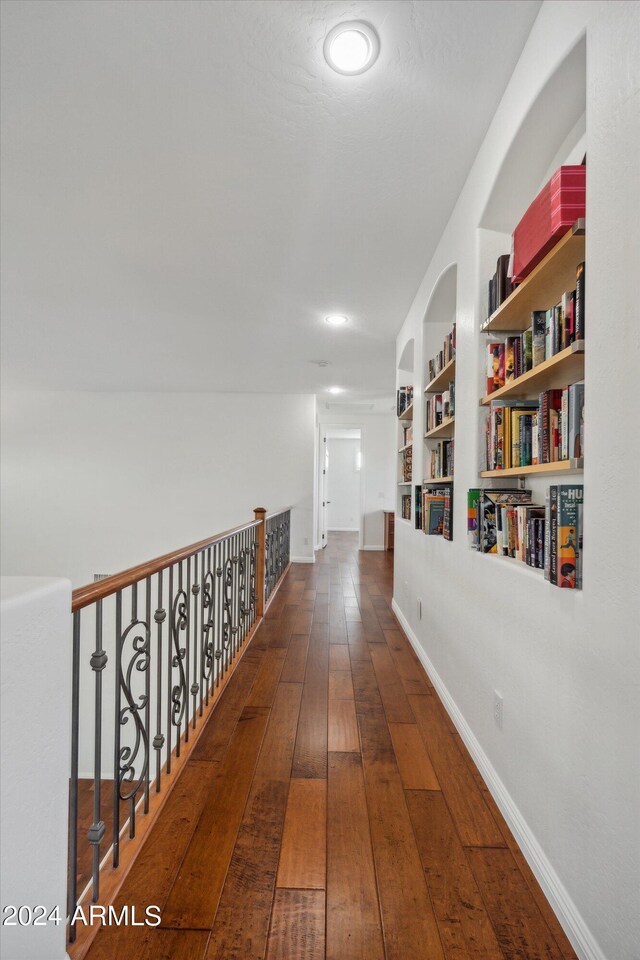 corridor with built in shelves and dark hardwood / wood-style flooring