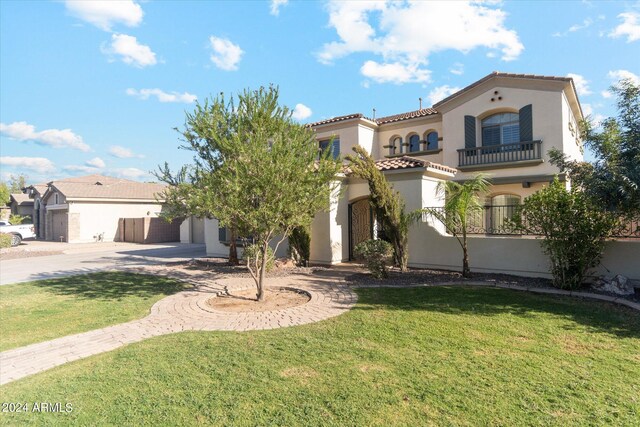 mediterranean / spanish home featuring a balcony, a garage, and a front yard