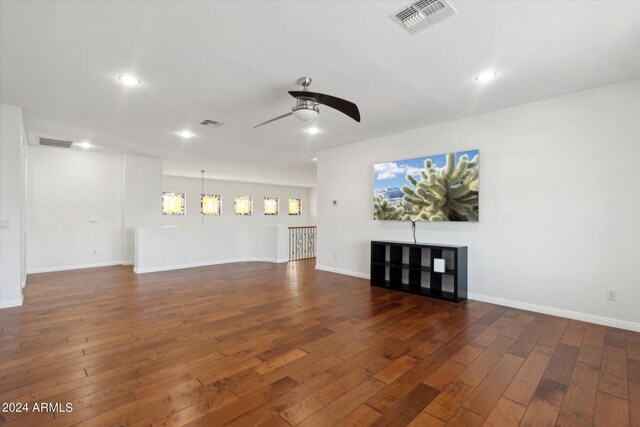 unfurnished living room featuring dark wood-type flooring and ceiling fan