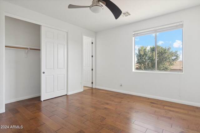 unfurnished bedroom with dark wood-type flooring, ceiling fan, and a closet